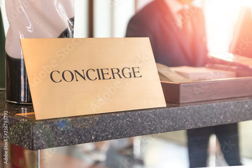 Concierge service desk counter with happy employee staff receptionist working in front of hotel with tourist guest business customer. photo