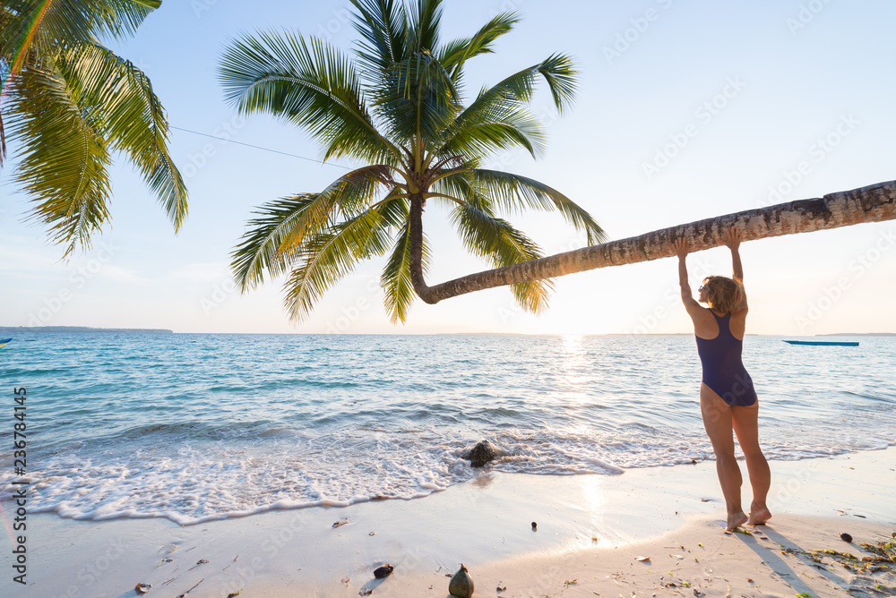 Woman relaxing under coconut palm frond on scenic white sand beach, sunny  day, turquoise transparent water, real people. Indonesia, Kei islands,  Moluccas Maluku, Wab beach Stock Photo | Adobe Stock