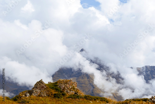 autumn mountain landscape of the Caucasus with rocky alpine meadows and distant mountain ranges in the clouds..