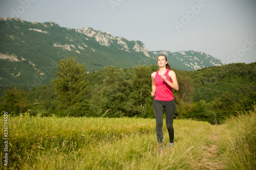 Beautiful young woman workout outdoor runs across meadow in early summer © Samo Trebizan
