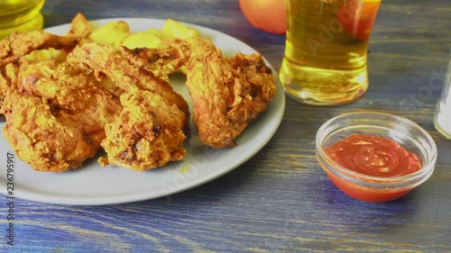 Crispy fried chicken wings with fried wedges on a plate. Breaded crispy chicken with baked potatoes for tasty dinner