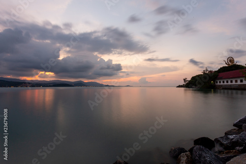 Fototapeta Naklejka Na Ścianę i Meble -  View of Big Buddha temple in the background and sandy beach with ocean in the foreground during sunset in Koh Samui, Surat Thani, Thailand
