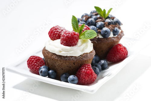 sweet chocolate cupcakes with fresh berries for dessert on white plate