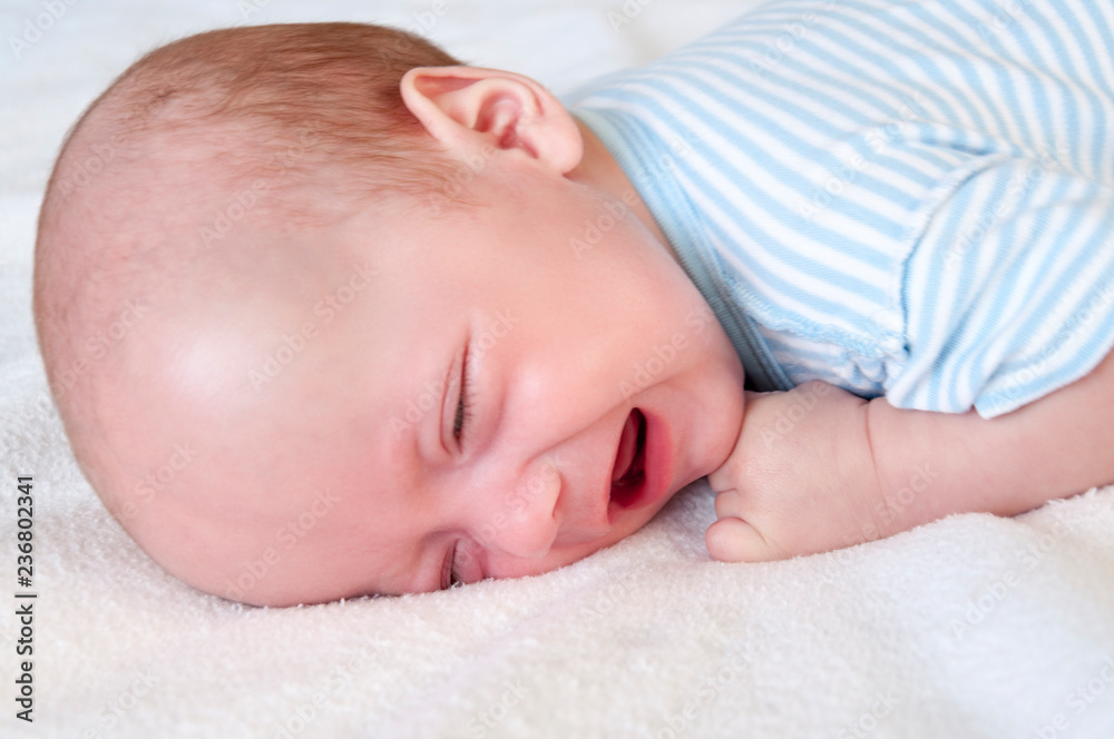 The baby cries and pulls the handle into his mouth because of the cutting teeth. Selective focus. The baby cries and pulls the handle into his mouth because of the cutting teeth. Selective focus.