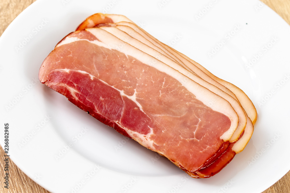 Raw ham on a white plate in the kitchen 