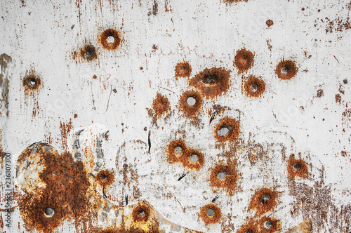 Texture of old rusty metal sheet with bullet holes on it