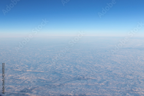 View of blue sky from horizon. View from the airplane porthole. Blue sky, white air clouds.