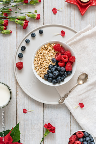 Breakfast, oatmeal with blueberry and raspberry on white bowl. Healthy food