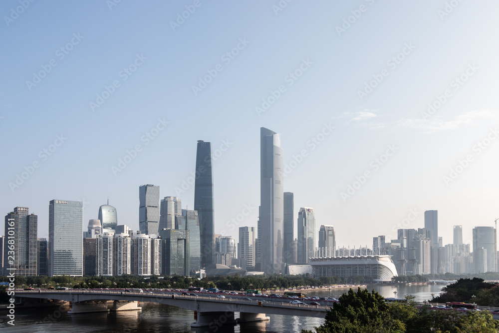 Modern city with skyscrapers. City buildings, a bridge across the river, driving cars on the bridge. High towers of a business center. Modern architecture of buildings.