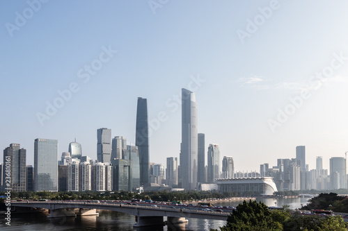Modern city with skyscrapers. City buildings  a bridge across the river  driving cars on the bridge. High towers of a business center. Modern architecture of buildings.