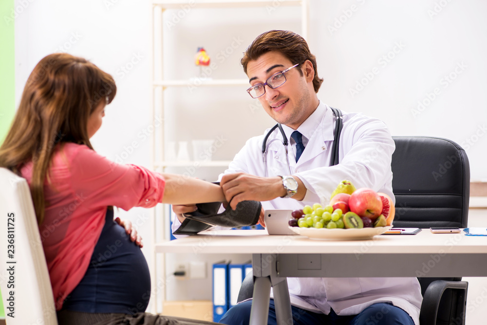 Pregnant woman visiting doctor discussing healthy diet Pregnant woman visiting doctor discussing healthy diet