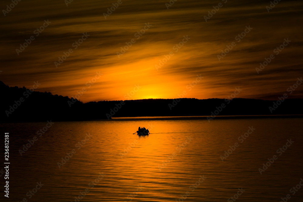 Breathtaking sunset landscape at a Chilean lake, with a boat in the middle of the orange light