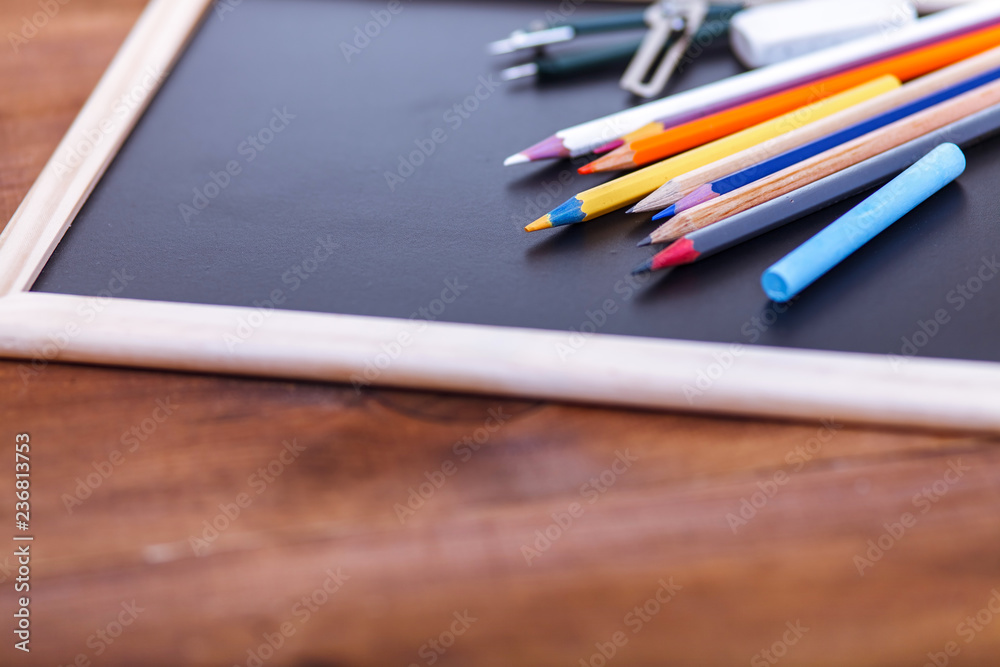 Back to school concept, colored pencils on black table, multicolored stationery accessories for educator teaching kid drawing on empty wooden desk, creative education background, top view, copy space Back to school concept, colored pencils on black table, multicolored stationery accessories for educator teaching kid drawing on empty wooden desk, creative education background, top view, copy space