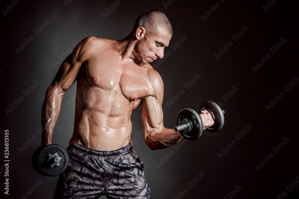 A man shakes his arm muscles. Man with dumbbells. Strong man. Strength exercises. Muscle man. Pumped up muscles. Muscle mass. Dumbbell. Sport equipment. A man shakes his arm muscles. Man with dumbbells. Strong man. Strength exercises. Muscle man. Pumped up muscles. Muscle mass. Dumbbell. Sport equipment.