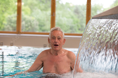 Senior man enjoying shower in pool
