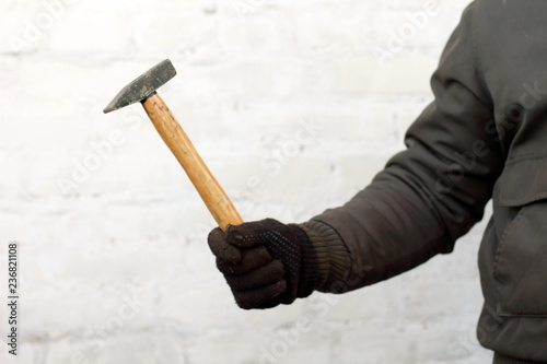 Hammer with wooden handle in man hand working in black gloves on white background close-up