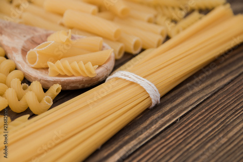 pasta of different types taken from the top and wooden spoon. Food background concept.
