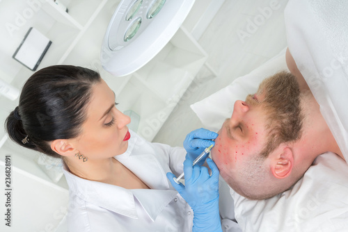 The doctor cosmetologist makes the Rejuvenating facial injections procedure for tightening and smoothing wrinkles on the face skin of a men in a beauty salon.Cosmetology skin care.