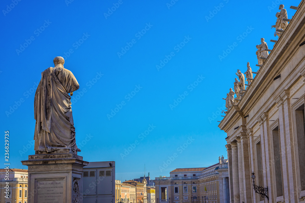 Fototapeta premium Statue of St. Peter in St. Peter's Square, Vatican City, with the front of the famous Basilica.