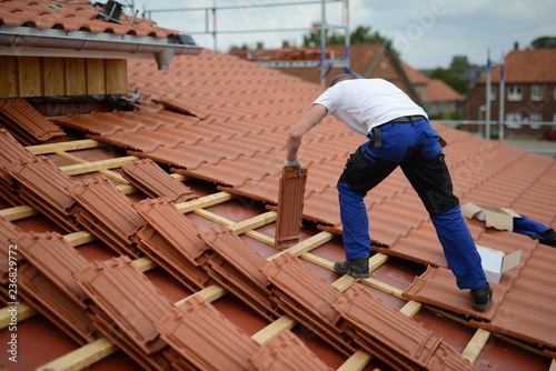 Dachdecker Bauarbeiter Mann auf Haus beim Ton Dachziegeln decken an der Arbeit photo