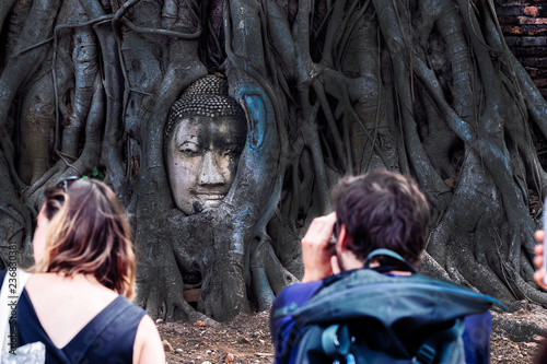 Buddha Head in Tree Roots with travelers take photo