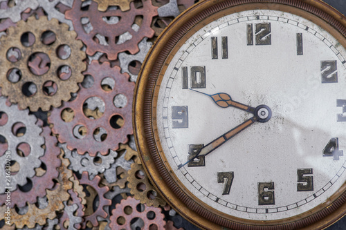 Antique pocket watch and old vintage hour metallic gears on natural stone background.