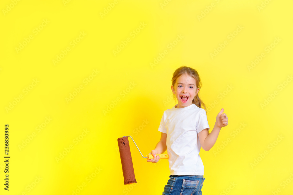funny girl with a roller for painting in her hands is playing the fool around the painted wall, shows a class funny girl with a roller for painting in her hands is playing the fool around the painted wall, shows a class