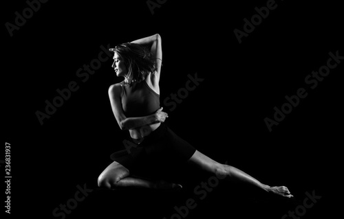 Young girl dancing in studio on isolated background in black and white