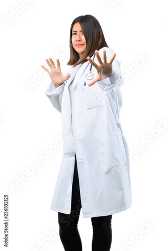 Doctor woman with stethoscope is a little bit nervous and scared stretching hands to the front on isolated white background