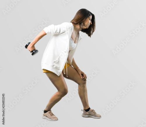 Full body of Sport woman making weightlifting on grey background