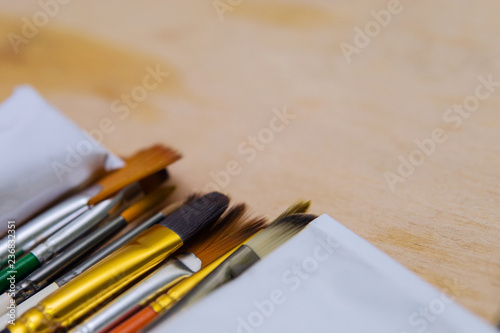 artistic colored paint brushes close-up drawing lie on a wooden palette