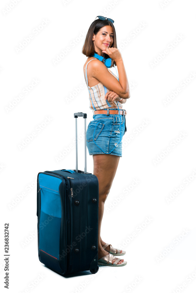 Full body of Girl traveling with her suitcase smiling a lot while putting hands on chest on isolated white background Full body of Girl traveling with her suitcase smiling a lot while putting hands on chest on isolated white background