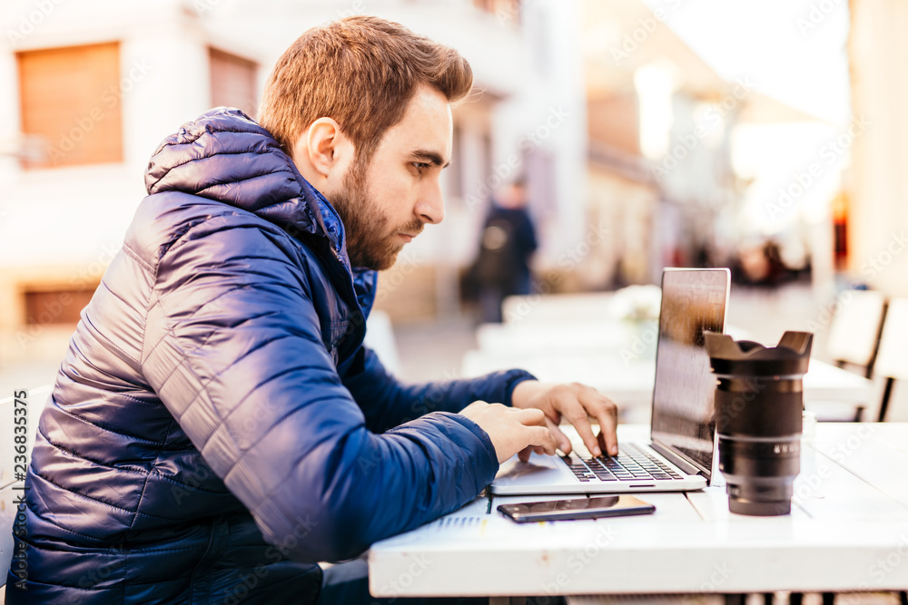 Modern lifestyle - young man wearing jacket working from outdoor office and staying connected with technology Modern lifestyle - young man wearing jacket working from outdoor office and staying connected with technology