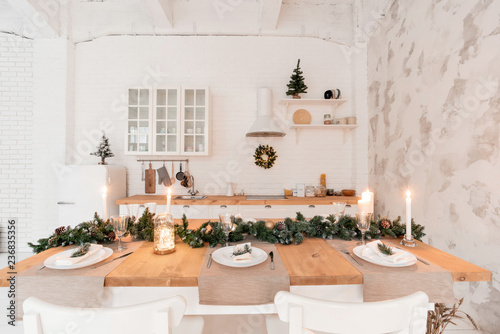 Loft style Apartment, large spacious living room with dining table and kitchen. Room with Christmas tree. Light white brick wall.