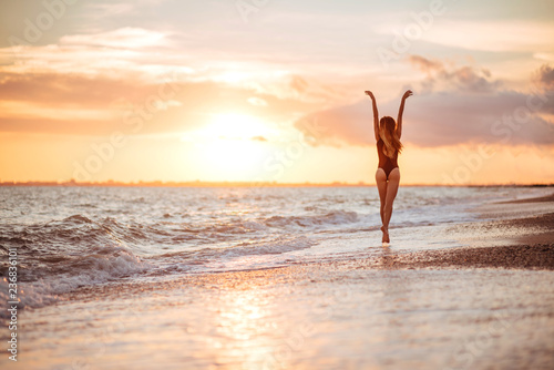 carefree woman dancing in the sunset on the beach. vacation vitality healthy living concept