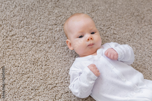 Childhood, infant and people concept - small baby lying on the floor photo