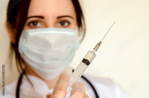 Young female doctor holds syringe for injection close up copy space