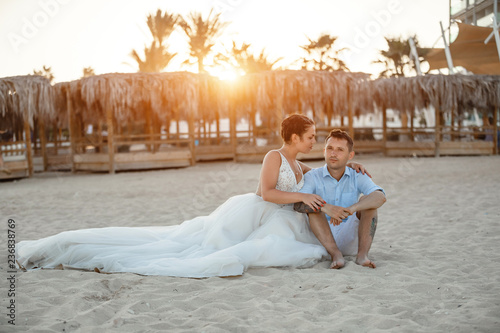 Beautiful smiling young bride and groom walking on the beach, kissing and having fun, wedding ceremony near the rocks and sea. Wedding ceremony on coast of Cyprus