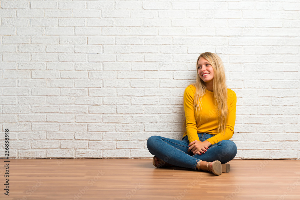 Young girl sitting on the floor looking over the shoulder with a smile Young girl sitting on the floor looking over the shoulder with a smile