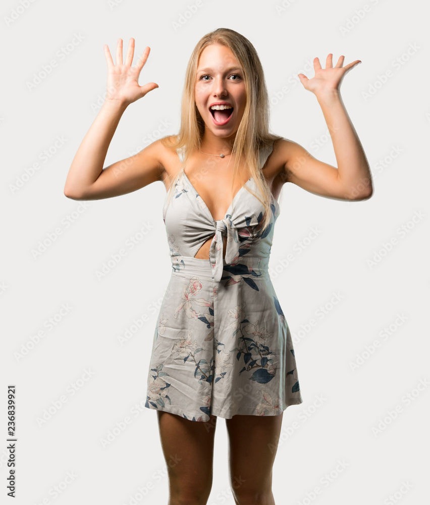 Young blonde woman with surprise and shocked facial expression. Gaping because can not believe what is happening on grey background Young blonde woman with surprise and shocked facial expression. Gaping because can not believe what is happening on grey background