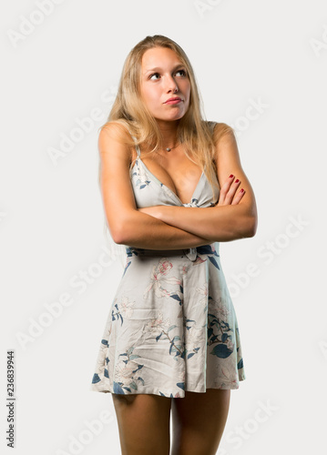 Young blonde woman making unimportant and doubts gesture while lifting the shoulders on grey background © luismolinero