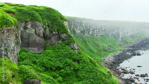 Green grass on a rocky cliff on the shore of the Pacific Ocean. Island Simushir, Kuril Islands. photo