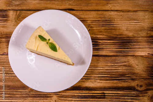 White plate with cheesecake New York and leaf of mint on wooden table. Top view