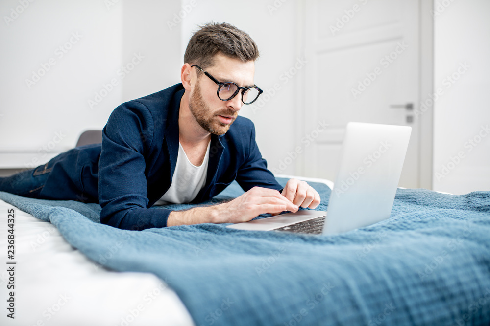Businessman dressed casually working with laptop at the hotel room or bedroom Businessman dressed casually working with laptop at the hotel room or bedroom