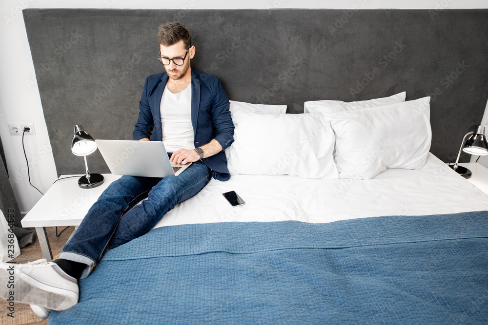 Businessman dressed casually working with laptop at the hotel room or bedroom