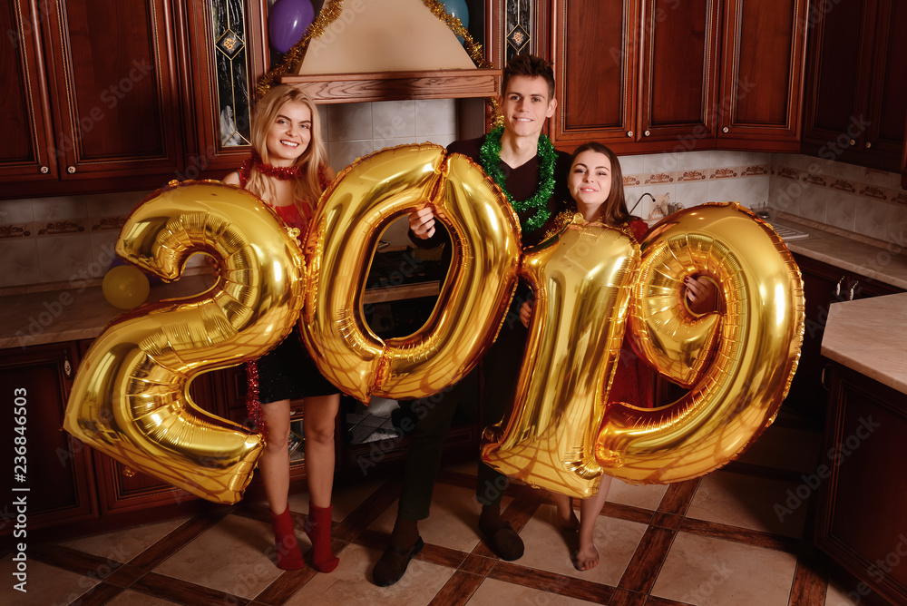 New 2019 Year is coming. Group of cheerful young people carrying gold colored numbers and have fun at the party