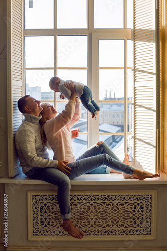 family in warm sweaters with his son sitting on the window in the winter