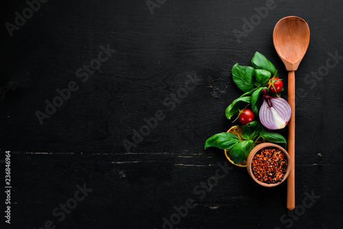 Fototapeta Naklejka Na Ścianę i Meble -  Fresh basil and spices. On a black wooden background. Top view. Free copy space.