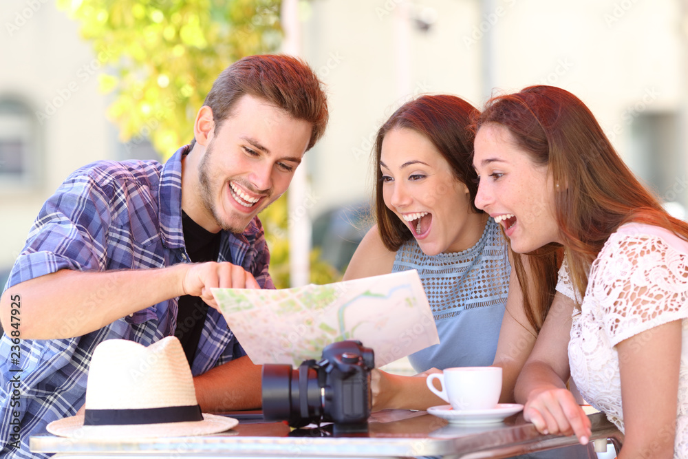 Three happy tourists checking guide in a coffee shop Three happy tourists checking guide in a coffee shop