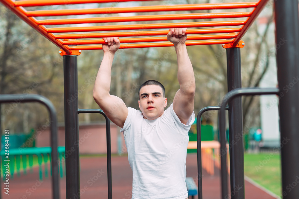 Obraz premium Fit man cross training on monkey bars . Fitness workout on brachiation ladder in an outdoor gym outside.